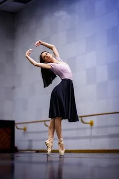 Ballet dancer performs in a practice space with wooden floors and mirrors Stock Photos