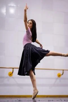 Ballet dancer practices in a dance studio wearing a pink shirt and black skirt Stock Photos