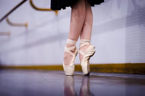 Ballet dancer practices on pointe shoes in a dance studio near a mirror during Stock Photos