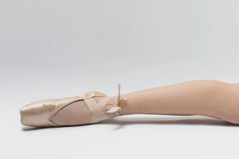 A ballet dancer practices on a studio floor. One foot is pointed with a balle Stock Photos