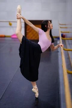 Ballet dancer practices in a studio with mirrors and wooden floor during Stock Photos