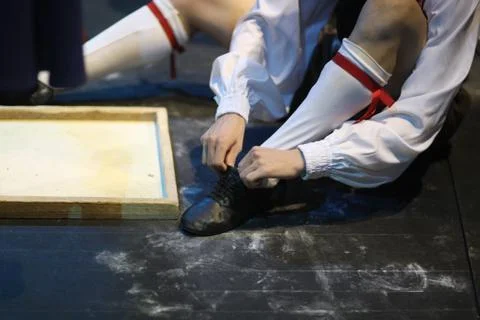 The ballet dancer, sitting on the floor, puts on special ballet shoes before  Foto stock