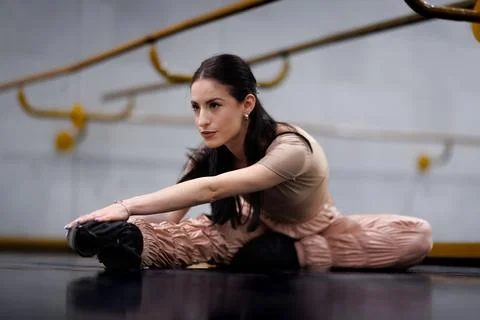 Ballet dancer stretches before practice in studio during morning hours with Stock Photos