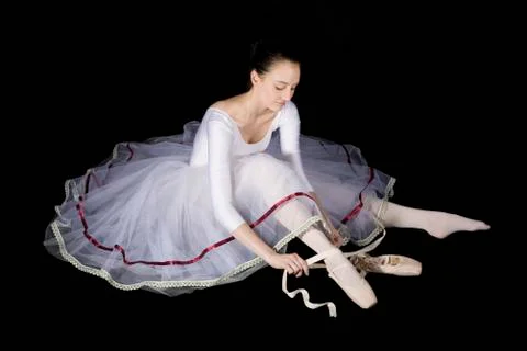 A ballet dancer tying her pointe shoe Stock Photos