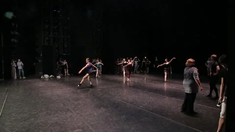 Ballet dancers are practicing turning jumps on a stage very long shot Stock Footage 93824598