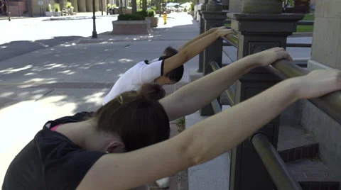Ballet Dancers Hold Onto A Railing Outside And Warm Up (4K) Stock Footage 52460083
