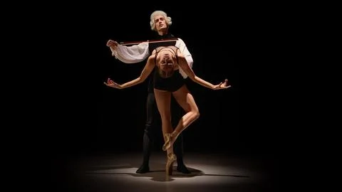 Ballet performer molded into instrument-inspired pose by classical mentor in Stock Photos