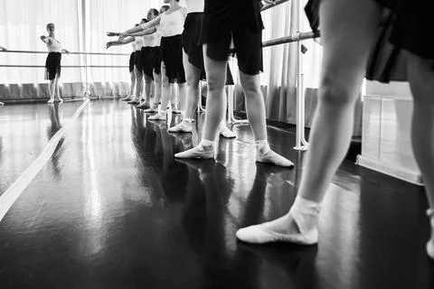 Ballet students practice barre positions in bright studio light Stock Photos