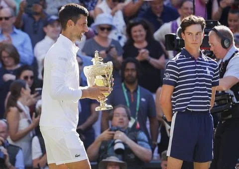 Balljunge schaut auf Champion Novak Djokovic mit dem Pokal, Trophäe, Siege.. Stock Photos