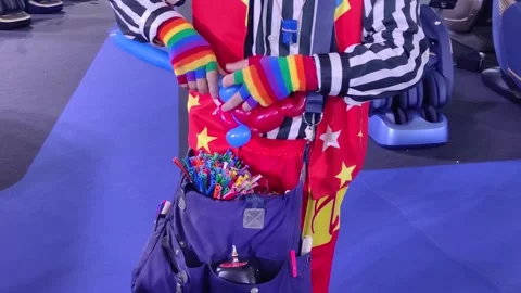 A balloon clown shaping or twisting a red balloon with both hands. 動画素材 321720680