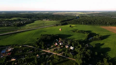 A balloon flies close to the ground over a residential village Stock Footage 205720259