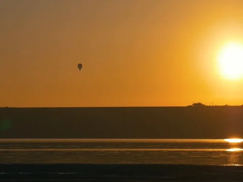 Balloon flying over the shore during gorgeous golden and orange sunset. Stock Footage 69840379