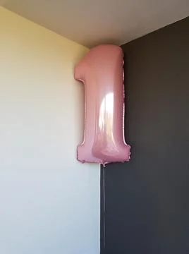 Balloon with the shape of number 1 in a corner of a gray and white wall Stock Photos