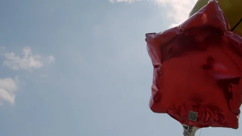 Balloons blowing in the wind with the sky behind. 4k60p Stock Footage 128847891