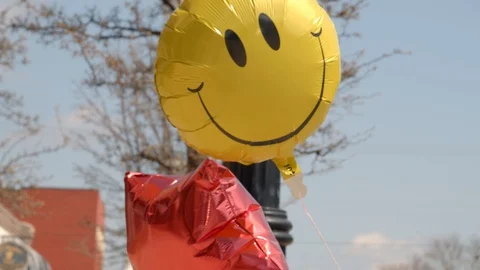 Balloons blowing in the wind in a small town on a sunny early spring day. 4k60p Stock Footage 128847984