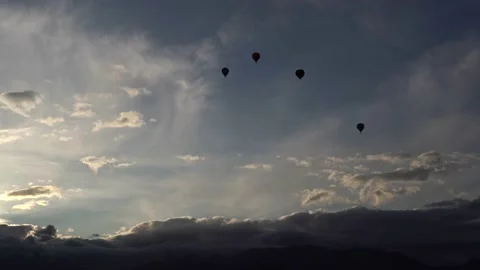 Balloons fly across the sky. A silhouette. Over the mountains. Sunrise. Clouds Stock Footage
