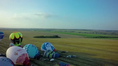 Balloons fly up in sky with passengers over green field Stock-Footage 66758692