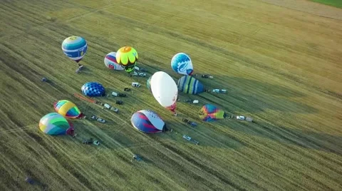 Balloons fly up in sky with passengers over green field Stock-Footage 66758862