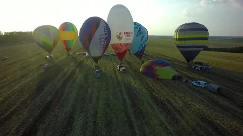 Balloons fly up in sky with passengers over green field Stock-Footage 66759658