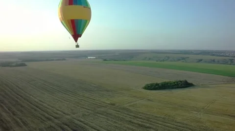 Balloons fly up in sky with passengers over green field Stock-Footage 66759935