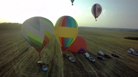 Balloons fly up in sky with passengers over green field Stock-Footage 66760028