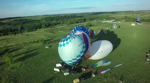 Balloons fly up in sky with passengers over green field Stock-Footage 66760313