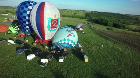 Balloons fly up in sky with passengers over green field Stock-Footage 66760441