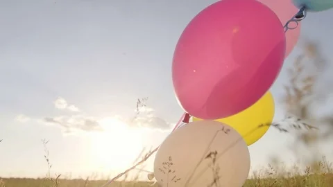 Balloons on a green meadow at sunset. Concept - lightness and freedom of Vídeo Stock 76156946
