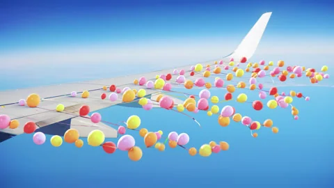 Balloons on strings attached to the wing of an airplane in flight Stock Footage 266419901