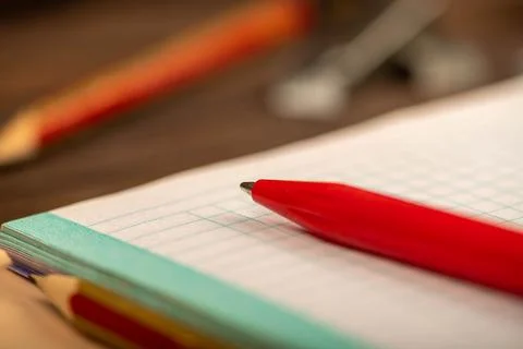 A ballpoint pen and a checkered notebook on a wooden table. Stock Photos
