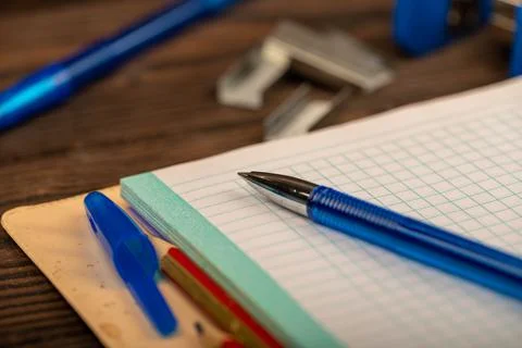 A ballpoint pen and a checkered notebook on a wooden table. Stock Photos