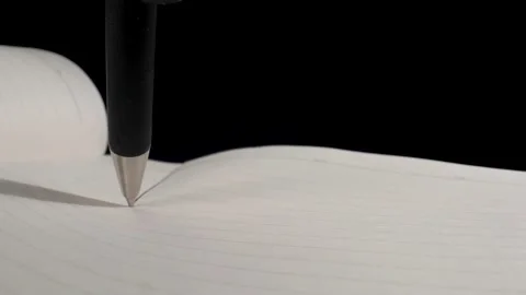 A ballpoint pen draws on a sheet of paper in a Notepad. Black background. Black  Видео 144907237