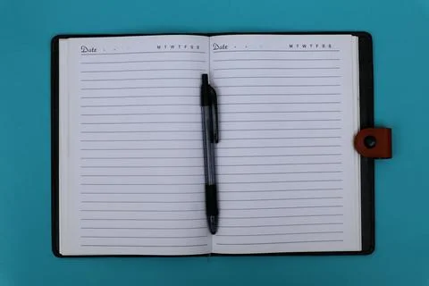 A ballpoint pen on a notebook is placed on the blue table. Stock Photos