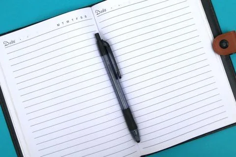 A ballpoint pen on a notebook is placed on the blue table. Stock Photos