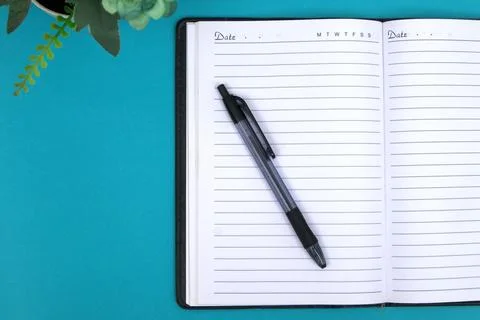 A ballpoint pen on a notebook is placed on the blue table. Stock Photos