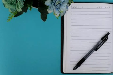 A ballpoint pen on a notebook is placed on the blue table. Stock Photos