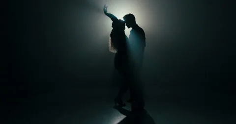Ballroom dance between two partners shadows of figures on stage in dark room lit Stock Footage 161628813