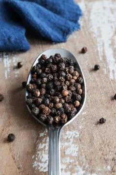 Balls of black pepper in a spoon on rustic background Stock Photos