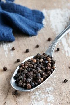 Balls of black pepper in a spoon on rustic background Stock Photos