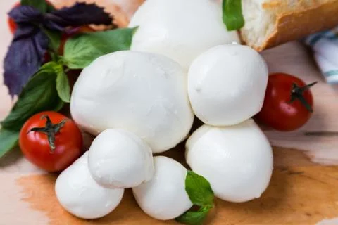 Balls mozzarella different size with tomatoes cherry, bread and basil on wood Stock Photos