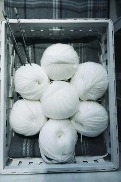Balls with woolen white threads and knitting needles in a basket Stock Photos