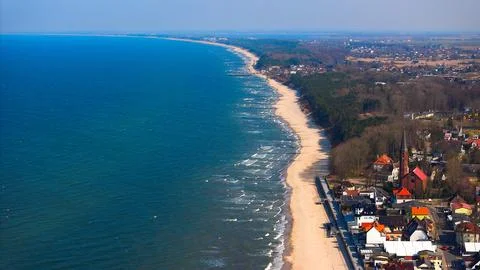 Baltic panorama with Sarbinowos red-brick church and sandy beach below. Stock Photos