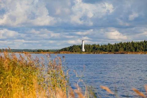 Baltic sea coast at sunset. Dramatic clouds, forest and small lighthouse. Stock Photos