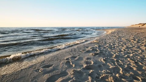 Baltic sea, sunset, sandy beach, soft waves, person walk Stock Footage 114216305