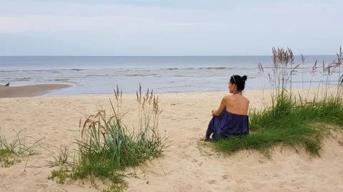 Baltic sea,woman on grassy sand dune, looking out to sea. Stock Photos