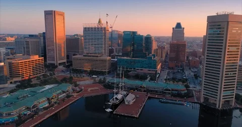 Baltimore's Inner Harbor glows at sunset, tall ships docked. USA Stock Footage 100016653