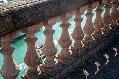Balustrade wall looking down the the water in the harbour and a boat passing Stock Photos