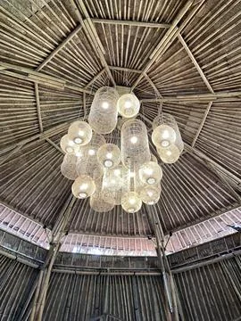 Bamboo ceiling frames a circular chandelier. Фото