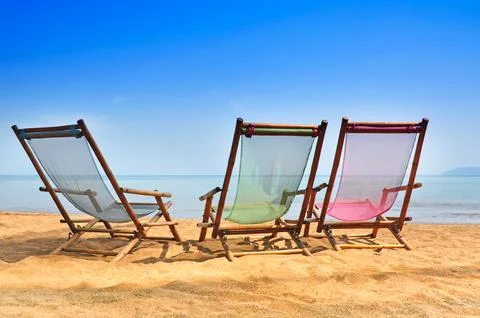 Bamboo deck chairs on the sandy beach with bright sun and waves, Island sou.. Фото