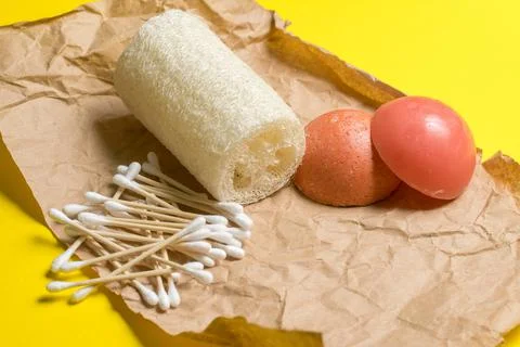 Bamboo ear sticks, loofah, solid shampoo and conditioner on kraft paper. Stock Photos